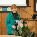 A woman holding a paper smiles at the camera